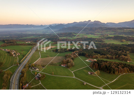 Aerial view of small scattered farm houses with red tiled roofs among green farming fields and distant mountain forest in summer. Aerial view of small scattered farm houses with red tiled roofs among green farming fields and distant mountain forest in summer. 129132314