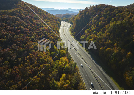 Aerial view of I-40 freeway in North Carolina leading to Asheville through Appalachian mountains in golden fall with fast moving trucks and cars. Interstate transportation concept 129132380