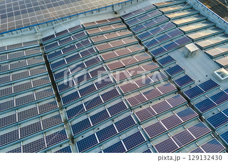 Aerial view of blue photovoltaic solar panels mounted on industrial building roof for producing green ecological electricity. Production of sustainable energy concept 129132430