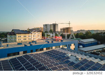 Aerial view of blue photovoltaic solar panels mounted on industrial building roof for producing green ecological electricity. Production of sustainable energy concept 129132432