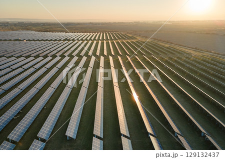 Aerial view of big sustainable electric power plant with many rows of solar photovoltaic panels for producing clean electrical energy at sunset. Renewable electricity with zero emission concept Aerial view of big sustainable electric power plant with many rows of solar photovoltaic panels for producing clean electrical energy at sunset. Renewable electricity with zero emission concept 129132437