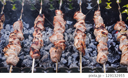 Beef meat is fried on skewers over an open fire. 129132955