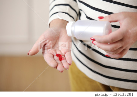 Close up 50 year old woman pouring out bottle pills time to take medication, treat memory loss, high blood pressure or cholesterol levels, pain medications, senile disease treatment concept Close up 50 year old woman pouring out bottle pills time to take medication, treat memory loss, high blood pressure or cholesterol levels, pain medications, senile disease treatment concept 129133291