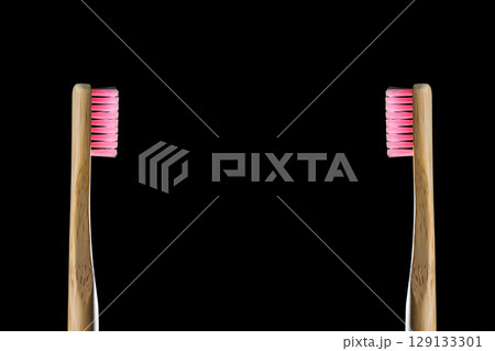 Eco friendly product concept. Zero waste two bamboo toothbrushes with pink bristle isolated on black background. Biodegradable material. Natural organic wooden brushes. Safe the earth. Copy space Eco friendly product concept. Zero waste two bamboo toothbrushes with pink bristle isolated on black background. Biodegradable material. Natural organic wooden brushes. Safe the earth. Copy space 129133301
