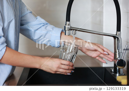 Filling glass of mains water, drinking water close-up. concept of pure drinking water. Water quality check concept. The concept of saving, problems with water Filling glass of mains water, drinking water close-up. concept of pure drinking water. Water quality check concept. The concept of saving, problems with water 129133319