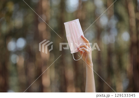 medical protective mask in girl's hand isolated on nature background. Face mask protection from viruses infection. Coronavirus - 2019. Health care concept. selective focus 129133345