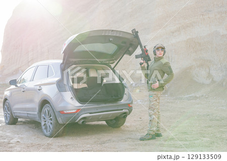 Female Soldier Holding Shotgun near Car with Open Trunk in Desert Area Female Soldier Holding Shotgun near Car with Open Trunk in Desert Area 129133509