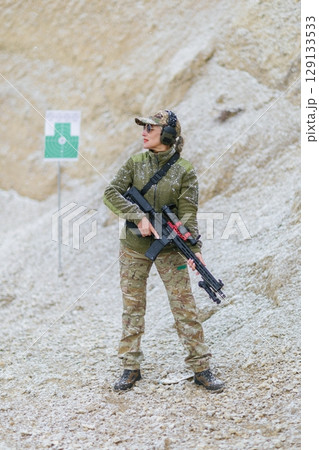 Female soldier holding a rifle during a military shooting training exercise in winter Female soldier holding a rifle during a military shooting training exercise in winter 129133533