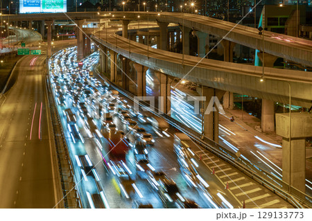 A night view with bright glowing light trails effect of many cars headlights and rear lights on urban expressway. 129133773