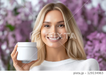 Portrait of a smiling well-groomed beautiful woman with a jar of moisturizer in her hands 129134963