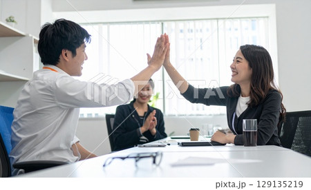 明るいオフィスでハイタッチするビジネスパーソン 明るいオフィスでハイタッチするビジネスパーソン 129135219