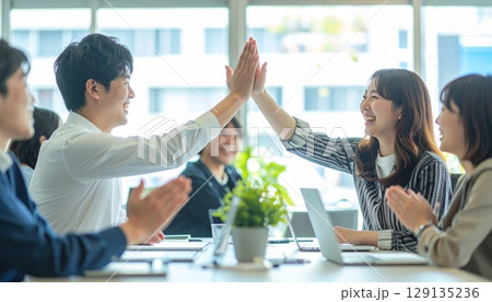 明るいオフィスでハイタッチするビジネスパーソン 129135236