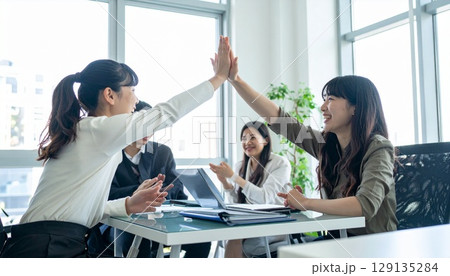 明るいオフィスでハイタッチするビジネスパーソン 129135284