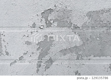 Peeling flaking paint on gray concrete wall. Cracked coating texture background. Dirty grunge surface backdrop. Repair concept. 129135786