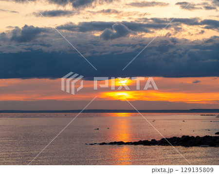 Scenic sunset at the beach. The sky is painted in bright colors. Dramatic cloudscape over the sea. Calm summer evening. Scenic sunset at the beach. The sky is painted in bright colors. Dramatic cloudscape over the sea. Calm summer evening. 129135809