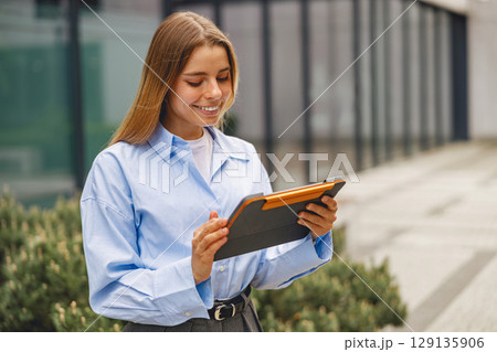 A Young Professional Engaged with a Tablet in an Outdoor Environment in a City Setting 129135906