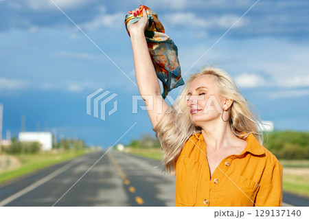 Blonde free woman is on the empty rural road in summer. Blonde free woman is on the empty rural road in summer. 129137140