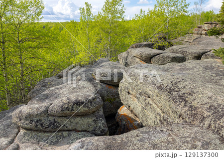 Ancient rock formation in a green forest, geological site. Ancient rock formation in a green forest, geological site. 129137300