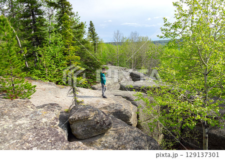 Boy is hiking in the prehistoric Rock formation in the green forest. 129137301