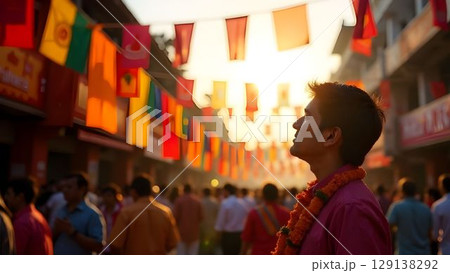 Crowd enjoying festive street atmosphere with colorful flags during sunset celebration in an urban area 129138292