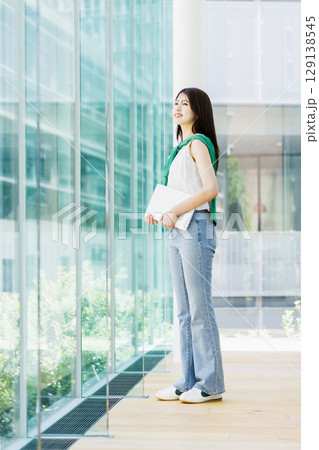 大学の教室でノートパソコンを持つ笑顔の女子大生 129138545