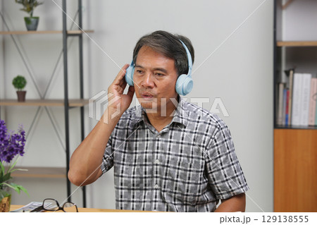 Asian senior man listening music by headphone. Asian senior man listening music by headphone. 129138555