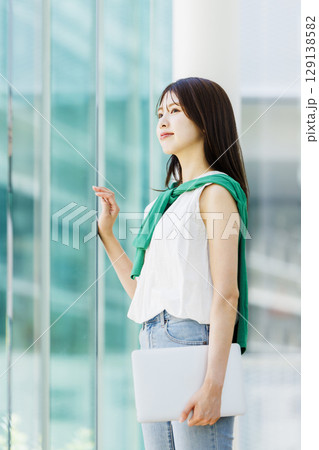 大学の廊下でノートパソコンを持つ笑顔の女子大生 大学の廊下でノートパソコンを持つ笑顔の女子大生 129138582