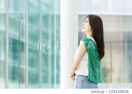 大学の廊下でノートパソコンを持つ笑顔の女子大生 129138656