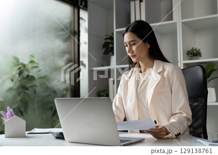 Professional Businesswoman Working in Modern Office with Laptop and Documents Professional Businesswoman Working in Modern Office with Laptop and Documents 129138761