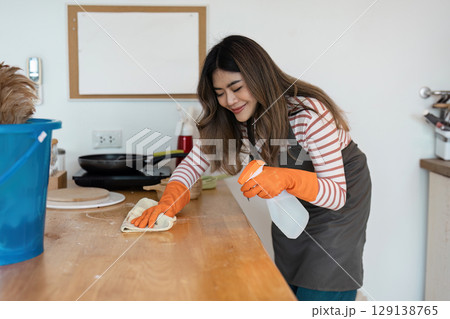 Professional Cleaning Service Worker Tidying Up a Modern Kitchen with Cleaning Supplies and Equipment for a Spotless Home Environment 129138765