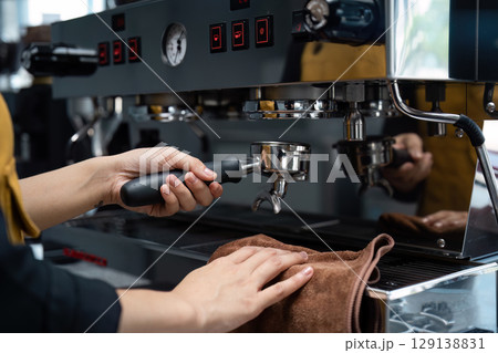 Barista Preparing Espresso with Professional Coffee Machine in Modern Cafe Setting Barista Preparing Espresso with Professional Coffee Machine in Modern Cafe Setting 129138831