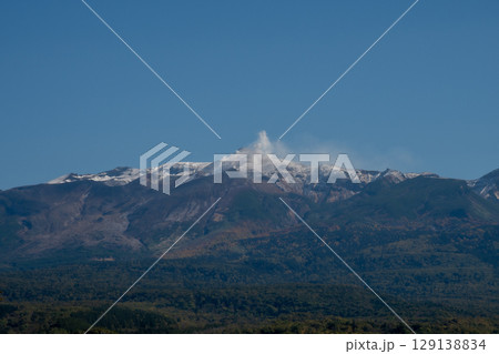 秋の晴れた日の森林地帯と冠雪の山頂　十勝岳 129138834