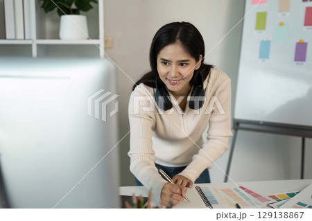 Creative Graphic Designer at Work with Color Swatches and Computer in Modern Office Environment Creative Graphic Designer at Work with Color Swatches and Computer in Modern Office Environment 129138867