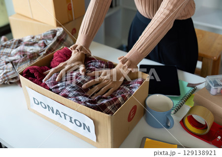 Hands Organizing Clothes in Donation Box for Charity and Community Support Hands Organizing Clothes in Donation Box for Charity and Community Support 129138921