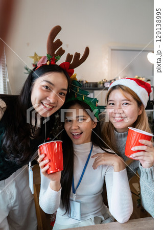 Festive Friends Celebrating Christmas with Red Cups and Holiday Accessories Indoors 129138995