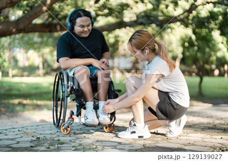 Young Woman Assisting Man in Wheelchair Outdoors, Embracing Inclusivity and Friendship in a Park Setting 129139027