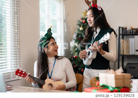 Festive Holiday Gathering with Friends Playing Ukuleles and Celebrating Christmas in a Cozy Living Room 129139028