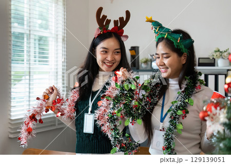 Festive Friends Decorating with Holiday Garlands and Cheerful Headbands in a Bright Living Room Setting Festive Friends Decorating with Holiday Garlands and Cheerful Headbands in a Bright Living Room Setting 129139051
