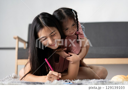 Young Child Engaged in Home Learning with Parent in a Cozy Living Room Setting 129139103