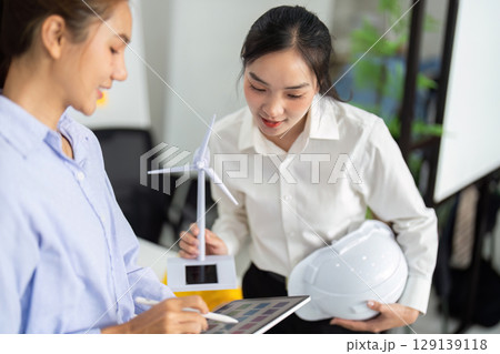 Sustainable Innovation. Female engineers collaborating on renewable energy projects in a vibrant workspace. 129139118