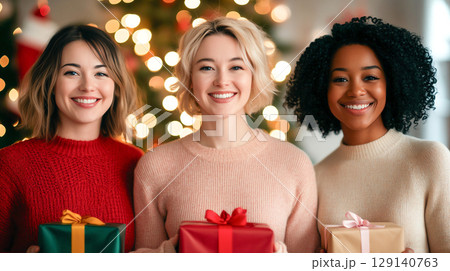 Joyful friends celebrating together with gifts presents in festive setting. Their warm smiles and holiday spirit create cheerful atmosphere 129140763