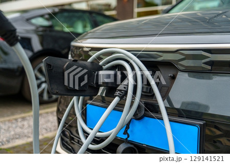 Electric Car Charging at Charging Station with Cable, Eco-Friendly Transportation 129141521