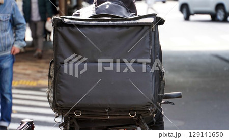 自転車の配達者が背負ったフードデリバリーの黒い宅配バッグ 自転車の配達者が背負ったフードデリバリーの黒い宅配バッグ 129141650