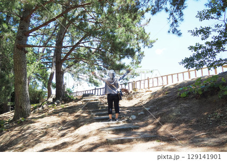 木々に囲まれた公園で両手を広げる女性 129141901