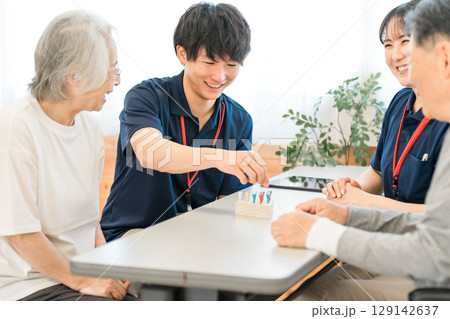 リハビリでシリンダーペグを使い手指機能訓練をするシニアと作業療法士の男女 リハビリでシリンダーペグを使い手指機能訓練をするシニアと作業療法士の男女 129142637