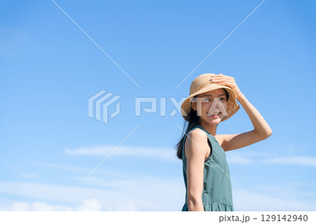 青空と麦わら帽子をかぶった若い女性 129142940