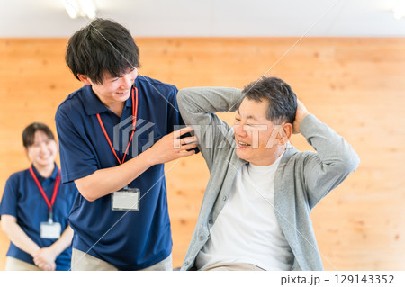 シニア男性に理学療法をせシニア男性に理学療法をせ術する理学療法士の男性術する理学療法士の男性スタッフ 129143352