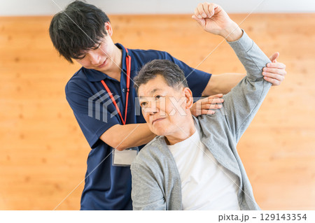 シニア男性に理学療法をせシニア男性に理学療法をせ術する理学療法士の男性術する理学療法士の男性スタッフ 129143354