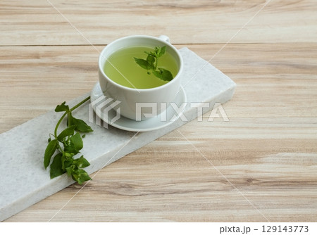 A cup of fresh tea from Chickweed, lat. Stellaria media on white marble. 129143773