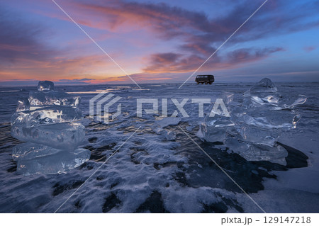 Sunset reflected in a large block of ice hummock on the frozen lake background. 129147218